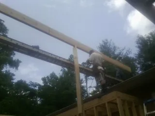 Carpenter setting a ridge beam over a new addition frame — Ice Dam Removal by Roofing Brothers in Calamus