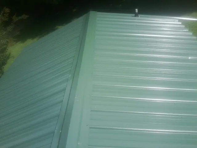 New green metal panels meeting at the ridge of a roof — Flat Roof Repair work by our crew in Calamus