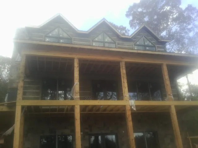 Dormers and porch framing on a large log home under construction — Roof Coating work by our crew in Calamus