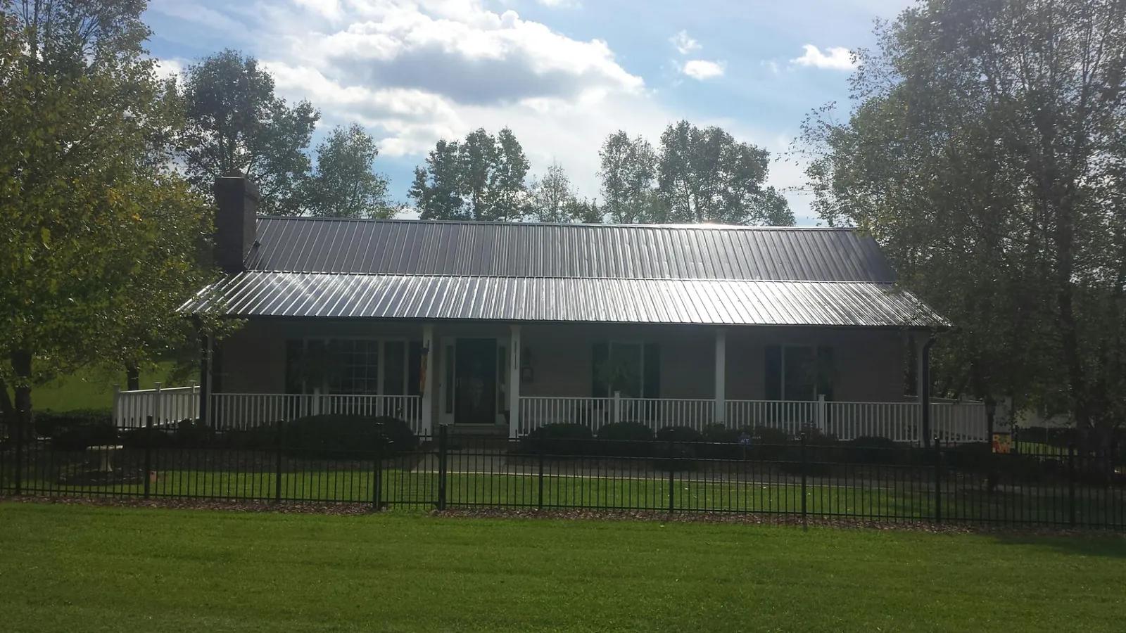 Gray metal roof on a brick ranch with a full width front porch — Gutter Guard Installation work by our crew in Calamus