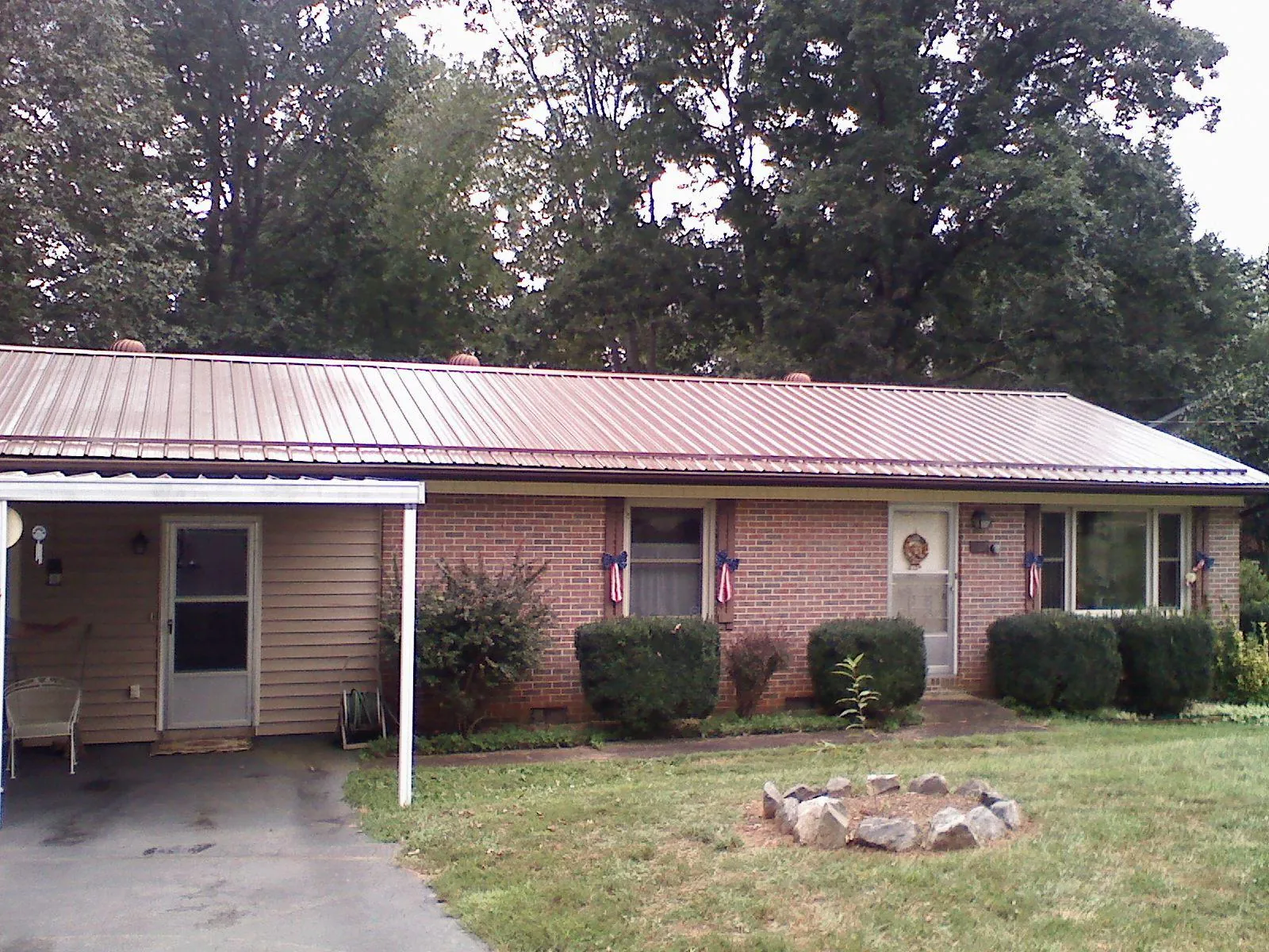 Bronze metal roof and carport on a brick ranch home — Roof Repair work by our crew in Calamus