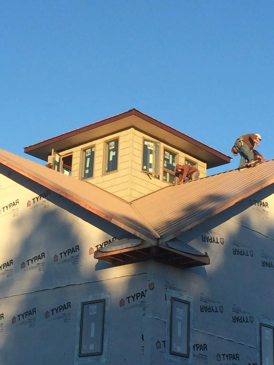 Roofers working around a rooftop cupola on a new metal roof at sunset — Roof Waterproofing in Calamus by Roofing Brothers